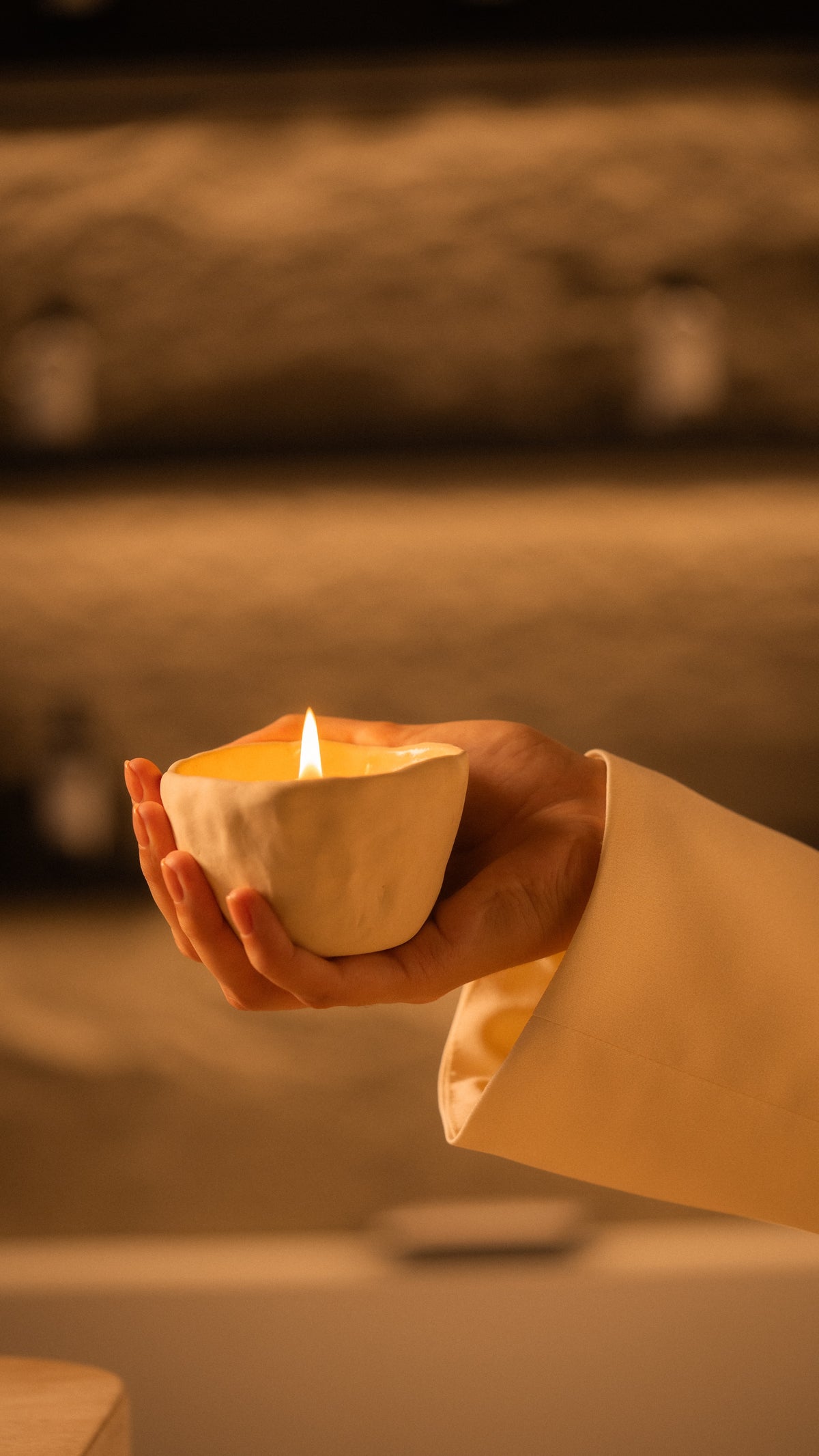 Hand holding the lit Ruby Oud candle
